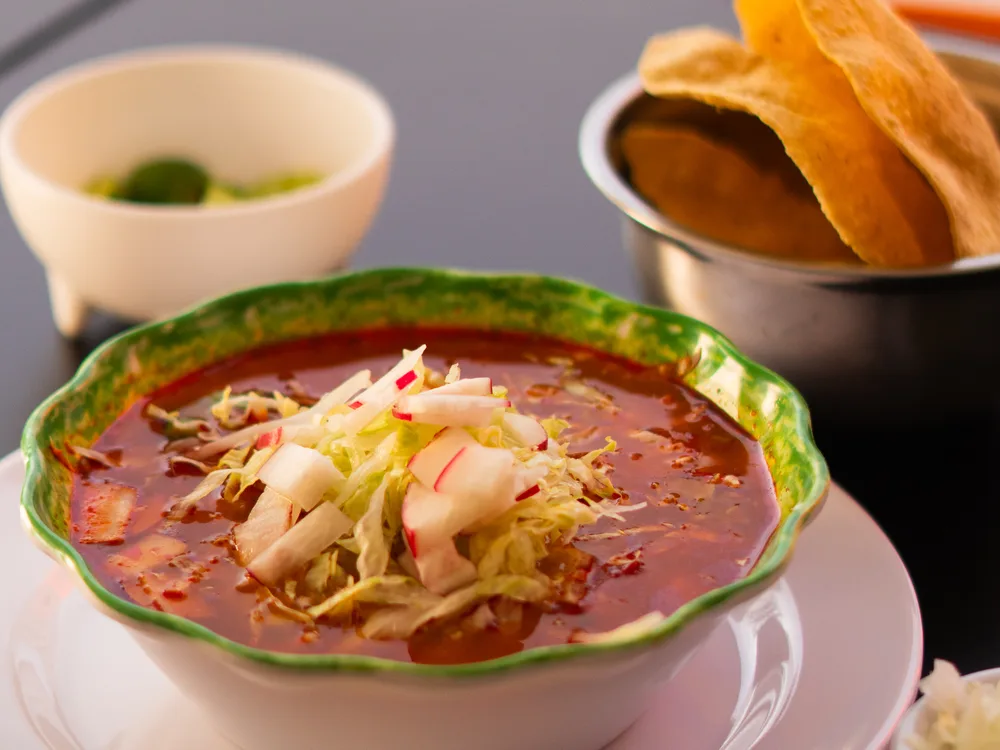 Bowl de pozole rojo con rábano, repollo y tostadas