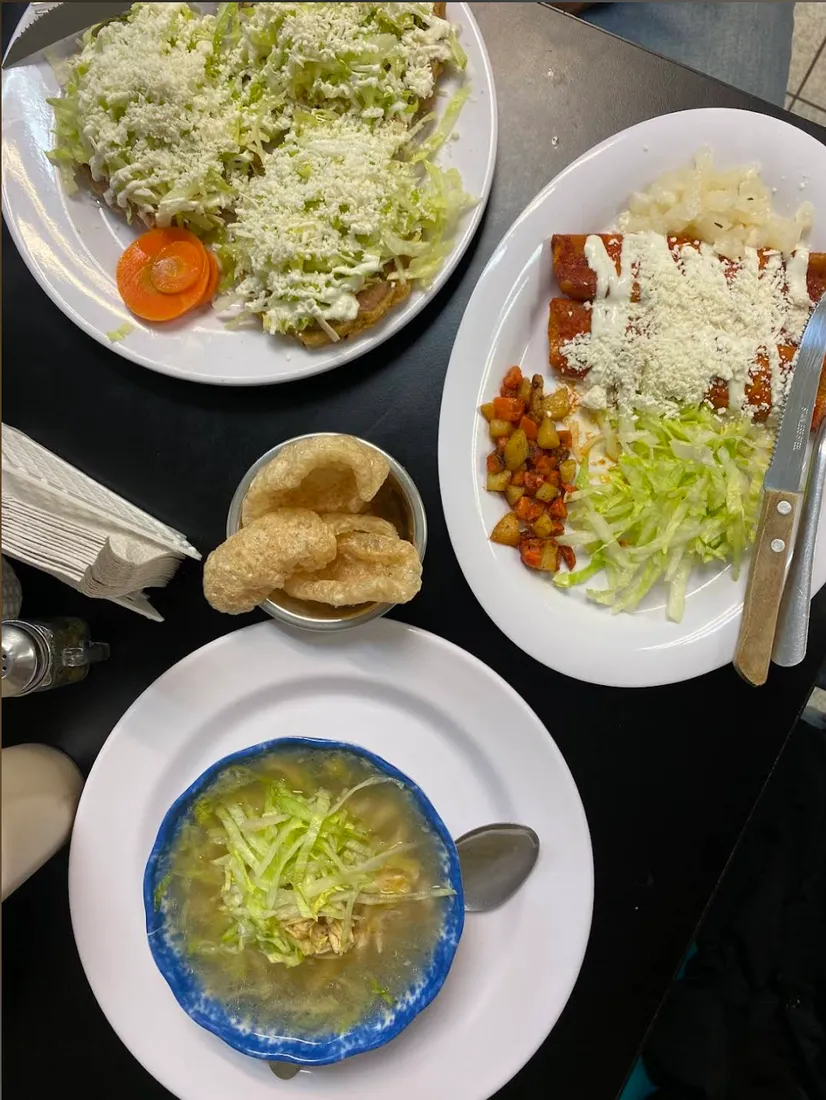 Mesa servida con enchiladas, sopes, chicharrón y pozole verde